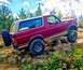 1995 Ford Bronco - A maroon Ford Bronco navigates a rocky trail under a cloudy sky.