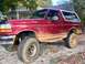 1995 Ford Bronco - This red Ford Bronco has seen some off-road action, evidenced by the mud covering its body and tires.
