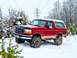 1995 Ford Bronco - A red 1995 Ford Bronco navigates a snowy terrain, its off-road capabilities.