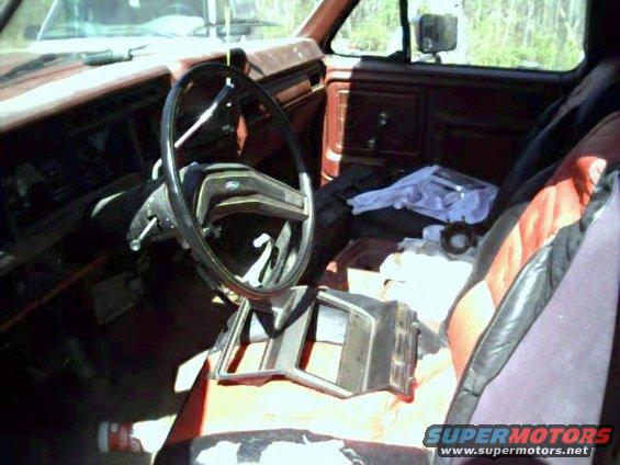 Interior of a red 1980s Ford truck, showing dashboard, steering wheel, and seats