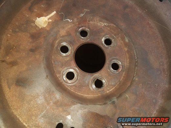 Rusty wheel hub with six bolt holes and a central circular opening