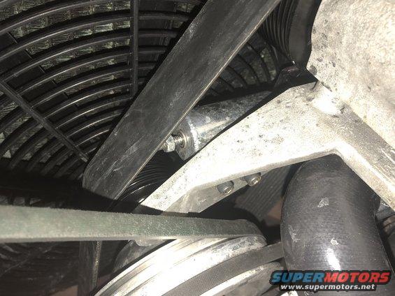 Engine fan with black blades and metal mounting bracket, drive belts, and pulleys