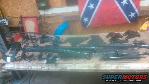 Various black painted vehicle suspension and steering components laid out on a table