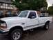 1995 Ford Bronco - White 1995 Ford F-250 pickup truck parked in a lot. Other vehicles are visible in the background.