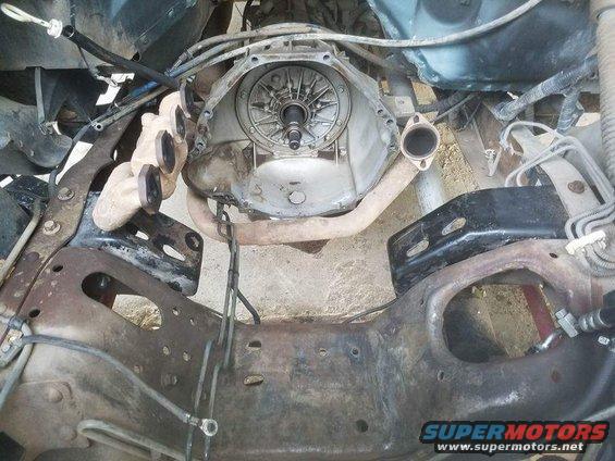 Transmission bell housing and exhaust manifolds on a vehicle frame
