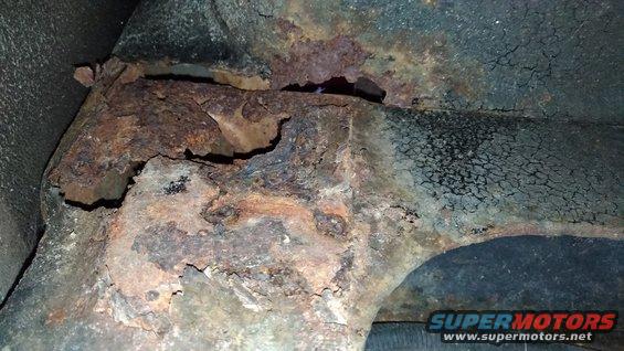 Close-up of heavily rusted metal frame components, possibly from under a vehicle