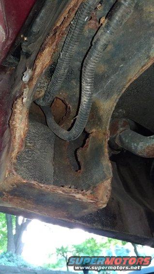 Close-up of heavily rusted metal frame and wiring harness on a vehicle
