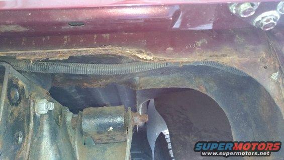 Close-up of rusted metal frame and wiring harness on a vehicle