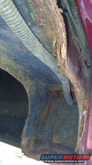 Close-up of heavily rusted metal frame and wiring harness on a vehicle's undercarriage