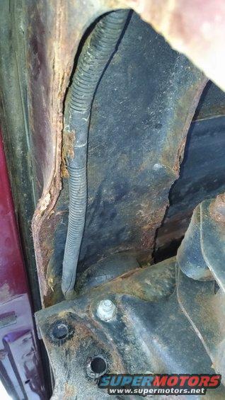 Close-up of heavily rusted vehicle frame and a black wiring harness