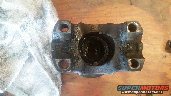 Close-up of a greasy driveshaft U-joint yoke with four bolt holes