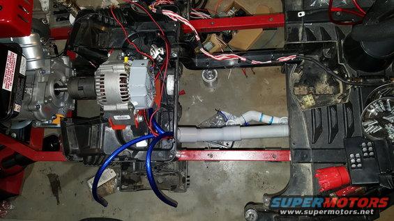 Generator and alternator assembly with wiring and plumbing components attached to a red frame