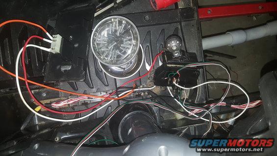 Close-up of wiring and two circular lights, one with screws inside a magnetic dish