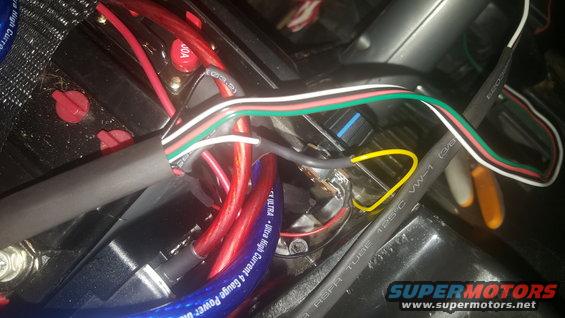 Close-up of a complex automotive wiring harness with red, white, green, and black wires, and a yellow loop. Some wires are labeled 'ULTRA High Current 4 Gauge Power'