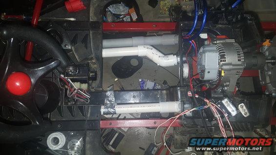 Custom wiring and PVC pipes connected to an alternator and other components