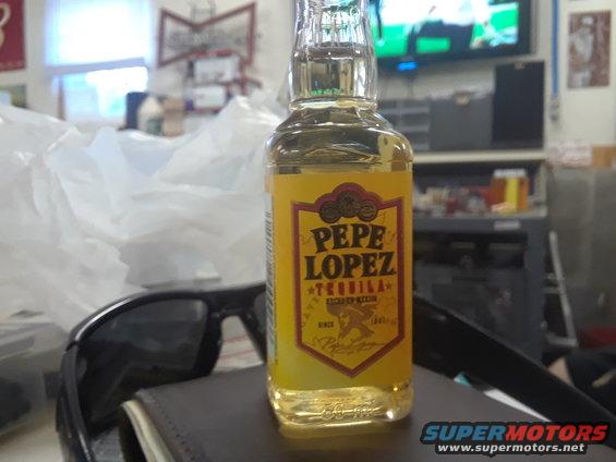Bottle of Pepe Lopez tequila on a table with sunglasses and a wallet