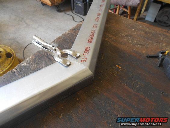 Metal tubing clamped at a 90-degree angle on a wooden workbench
