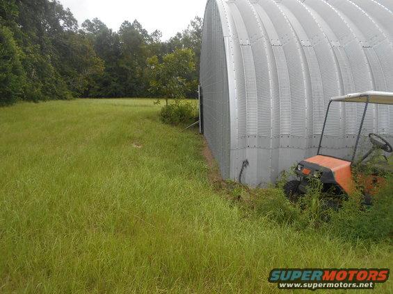 Orange golf cart parked next to a corrugated metal building