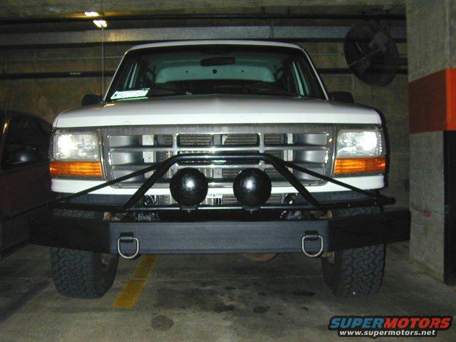 White Ford Bronco with aftermarket bumper and lights, parked indoors