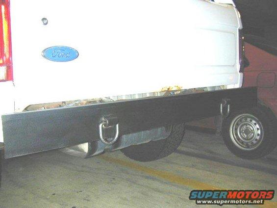 White Ford truck bed with a black flatbed attachment and a spare tire visible