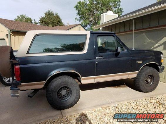 Side view of a 1994 Ford Bronco with a dark blue body and tan top