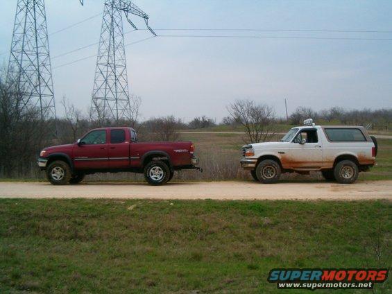 1996 Ford Bronco and red Toyota Tundra parked on dirt road with power lines overhead