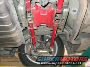 Undercarriage view of red suspension components and rear wheel
