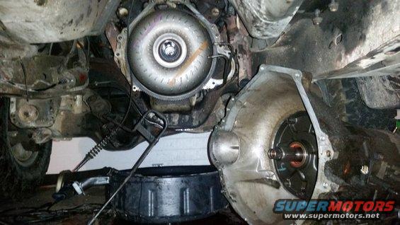 Underside view of a disassembled vehicle transmission and torque converter with a drain pan