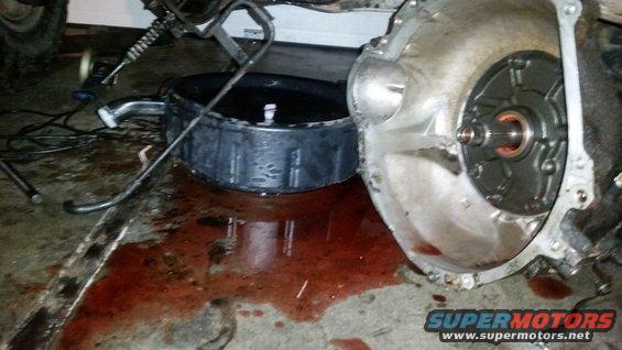 Transmission fluid spilled on concrete floor next to a transmission part. Drip pan is visible
