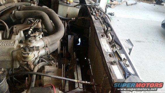 Engine bay showing radiator, fan, and hoses. Tools are on the fender