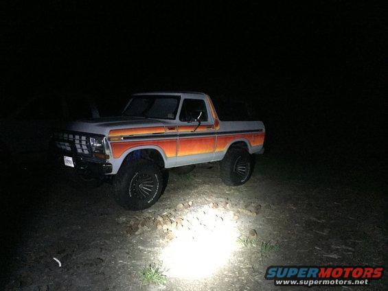 Gray Ford Bronco with orange and red stripes, lifted on black wheels, parked at night
