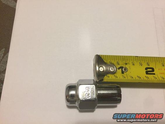 Chrome lug nut with 1/2-20 marking next to a tape measure showing 1 inch