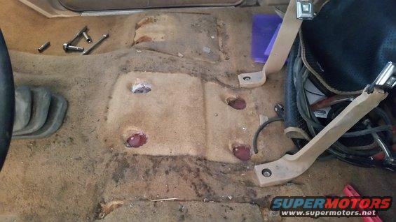 1985 Ford Bronco interior carpet removed, showing bolt holes and some tools