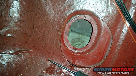 Close-up of red painted vehicle chassis with a circular opening and a bolt visible inside