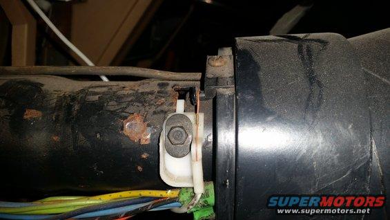 Close-up of rusty metal and wiring harness connected to a black plastic component