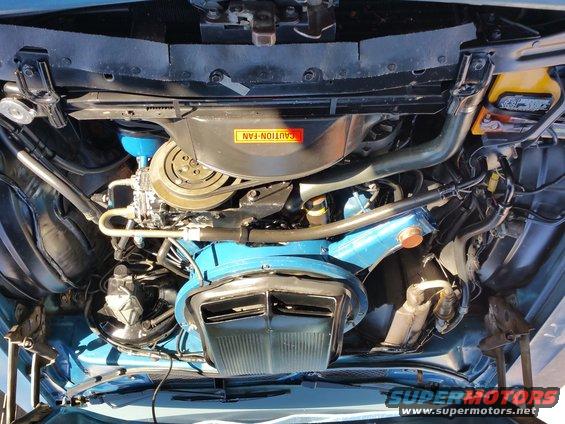 1973 Ford Ranchero engine bay with blue painted components and a yellow battery