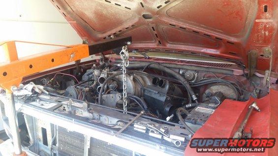 Engine bay with engine hoist and tools, red vehicle