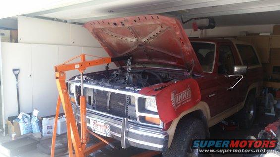 1985 Ford Bronco in garage with hood open, engine hoist positioned over engine bay