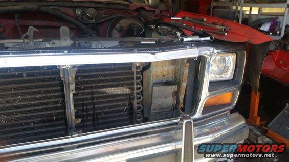 Red Ford Bronco front grille and headlight assembly with tools on the hood