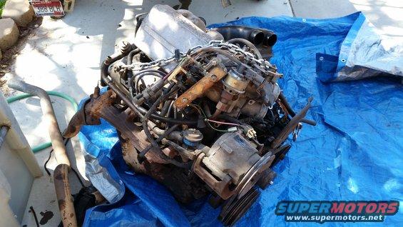 Engine assembly on a blue tarp, with exhaust pipe to the left