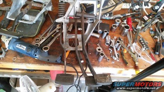 Clutch and brake pedals with tools and a drill on a workbench