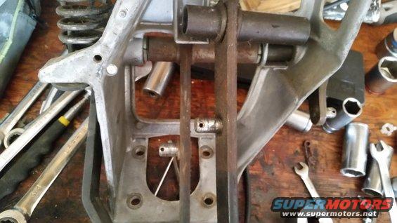 Close-up of a metal automotive component on a wooden workbench with various wrenches and sockets