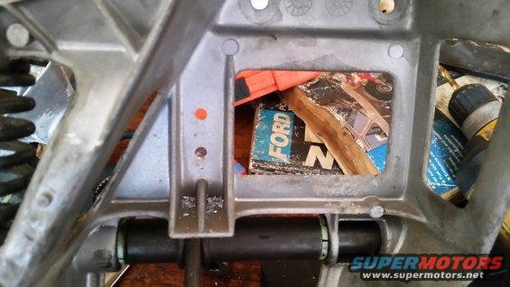 Close-up of a metal vehicle part with a book showing the word 'FORD' visible inside