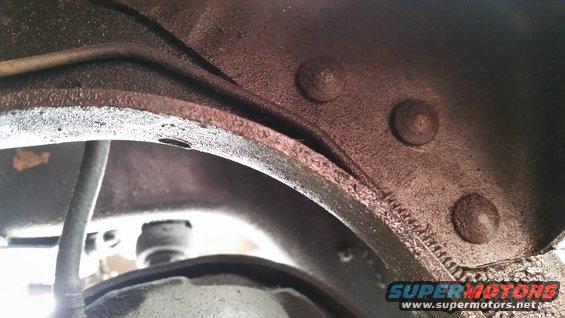 Close-up of vehicle frame underside showing brake lines and rivets