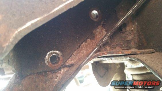 close-up of rusted metal frame with a brake cable running through it