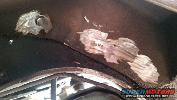 Patches of metal repair on a dark underbody surface, with some bolts visible