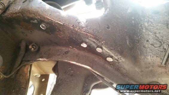 Close-up of a heavily rusted metal frame section with several bolts visible