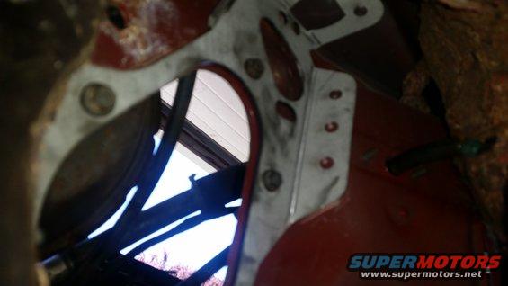 close-up of metal bracket attached to red vehicle frame, wires visible