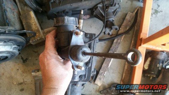 Clutch master cylinder assembly held in hand, with transmission parts in background