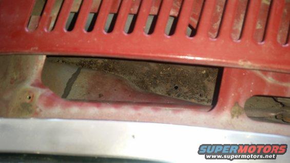 Red grille and vent area with visible dirt and debris